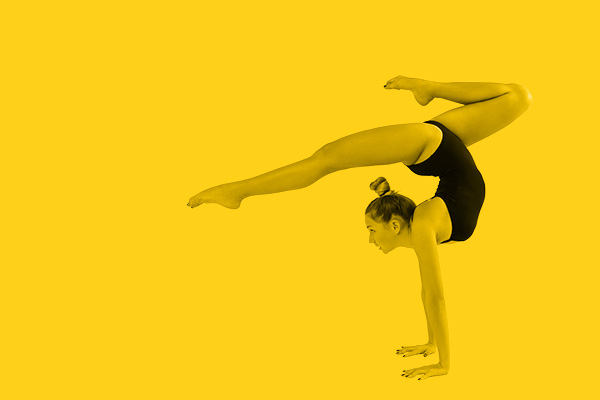 Billede af gymnastikpige som står på hænder og svinger det ene ben ud i en balanceakt. Billedet er fritlagt i photoshop og tonet samme farve som en gul ensfarvet baggrund. 